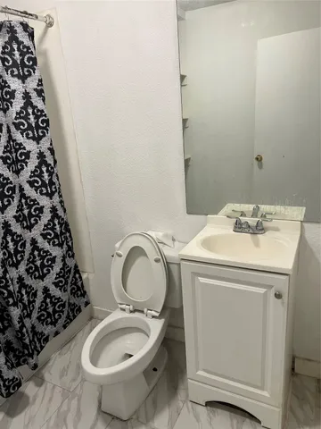 a bathroom with a granite countertop toilet and a sink