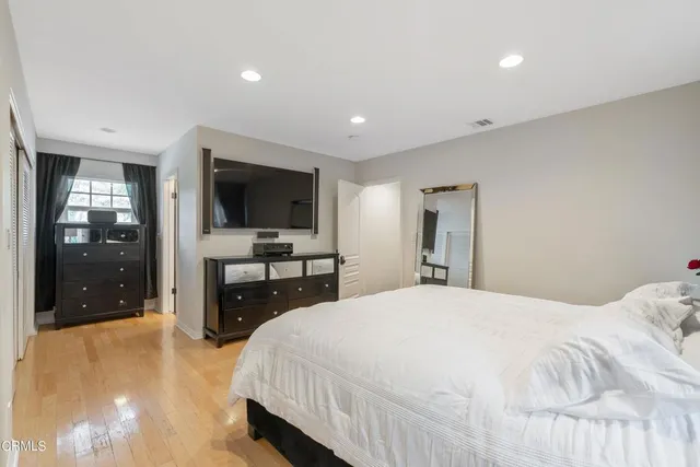 a bedroom with a bed and a flat tv screen on dresser