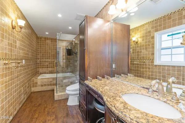 a bathroom with a granite countertop sink a toilet a mirror and shower