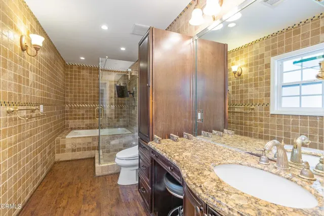 a bathroom with a granite countertop sink a toilet a mirror and shower