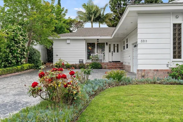 a front view of a house with a big yard and a large tree