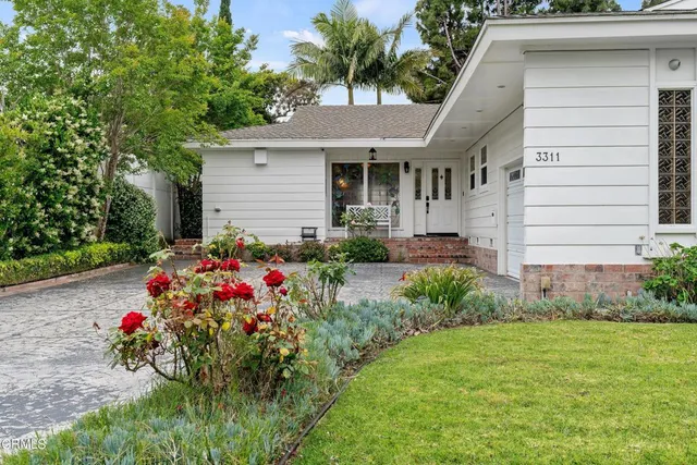 a front view of a house with a big yard and a large tree