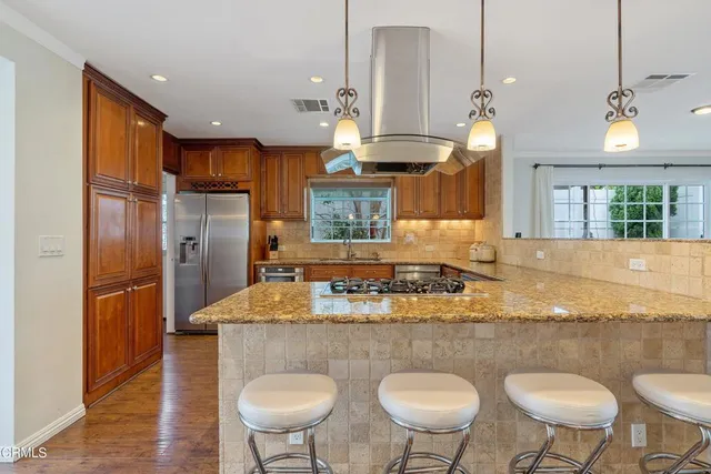 a kitchen with stainless steel appliances granite countertop a kitchen island a table and chairs in it