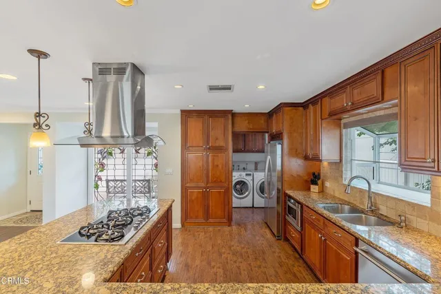 a kitchen with stainless steel appliances kitchen island granite countertop a sink stove and refrigerator