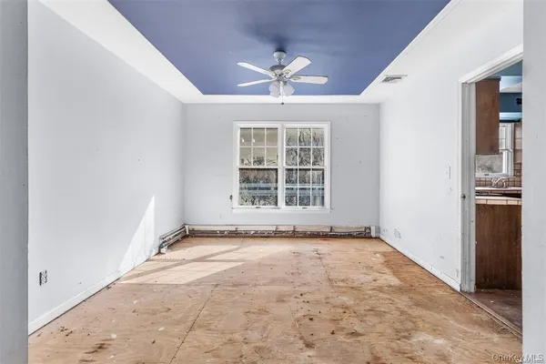 an empty room with windows and ceiling fan