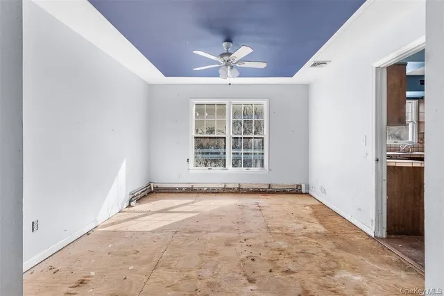 an empty room with windows and ceiling fan