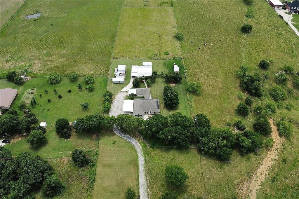 3007 McReynolds Road Sanger, TX 76266 - Photo 36 of 39 Aerial perspective featuring a primary residence with solar panels, multiple outbuildings, and a winding driveway