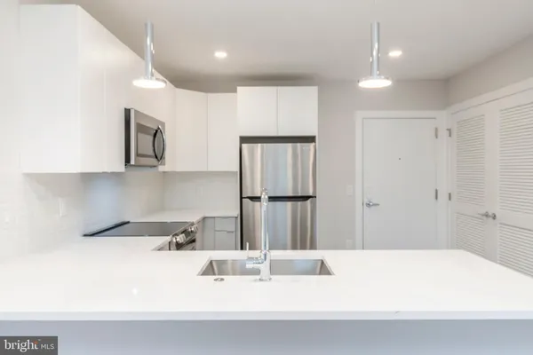 a kitchen with kitchen island granite countertop a sink and refrigerator