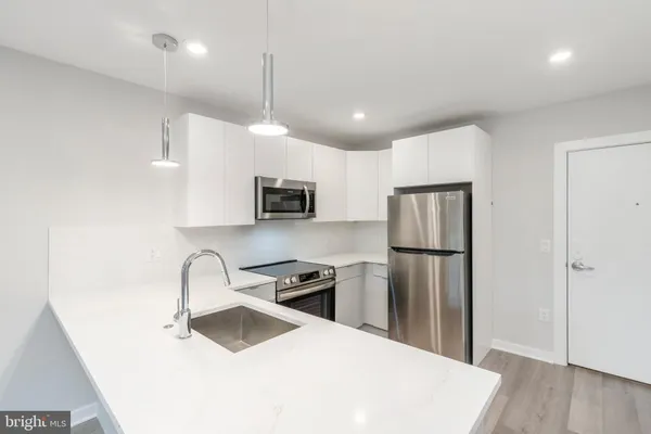 a kitchen with kitchen island a sink appliances and wooden floor