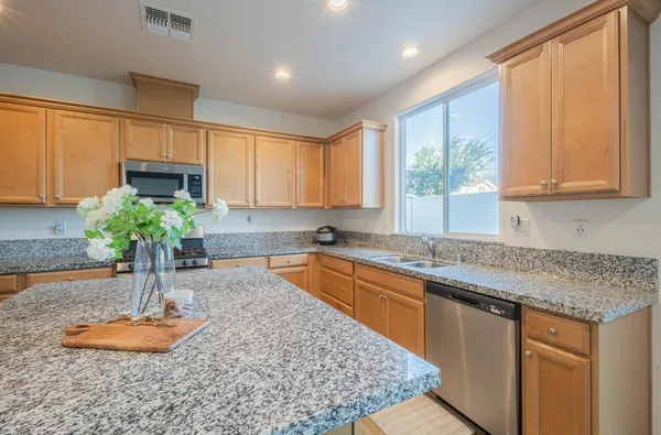 a kitchen with stainless steel appliances granite countertop a sink a window and a counter top space