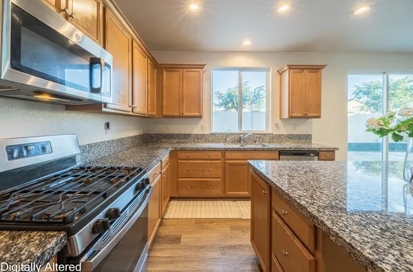 a kitchen with stainless steel appliances granite countertop a stove a sink and a microwave