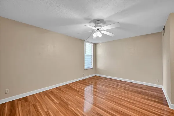 a view of empty room with wooden floor and fan