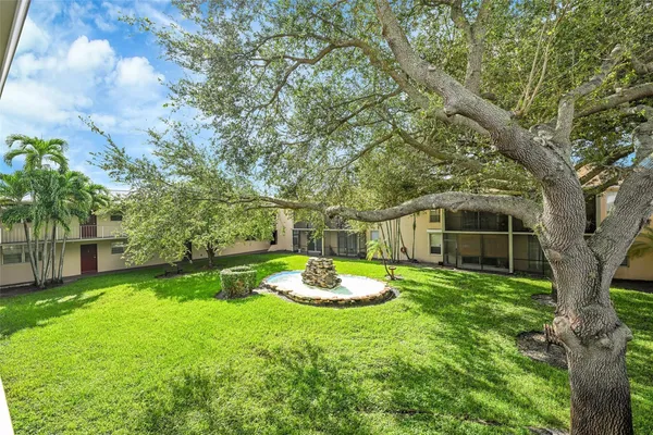 a backyard of a house with a fountain plants and large tree