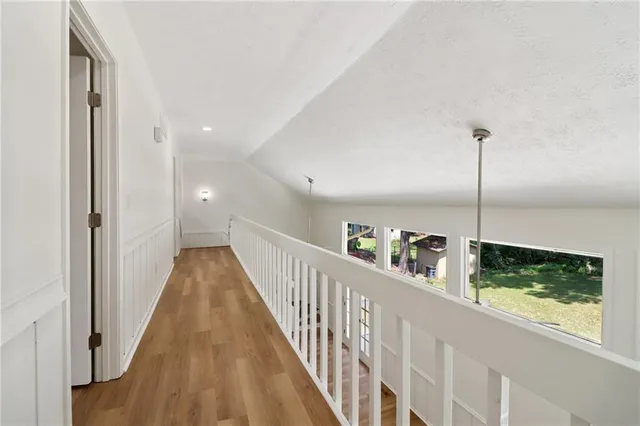 an empty room with wooden floor chandelier fan and windows