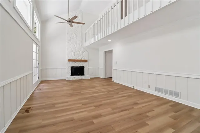 an empty room with wooden floor fan and windows