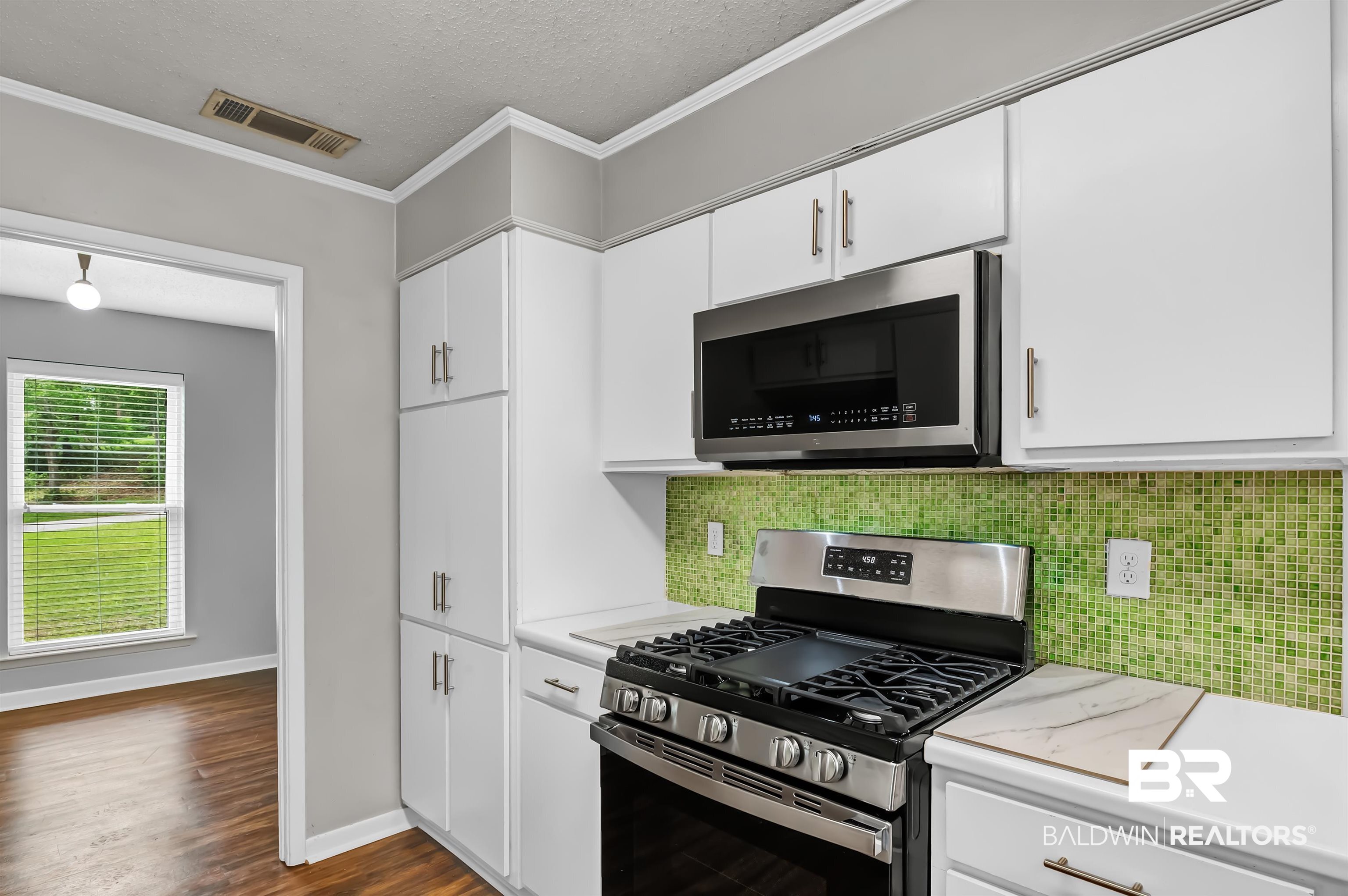 28 Caisson Trace Spanish Fort, AL 36527 - Photo 21 of 51 Kitchen with stainless steel appliances, decorative backsplash, visible vents, white cabinetry, and light countertops