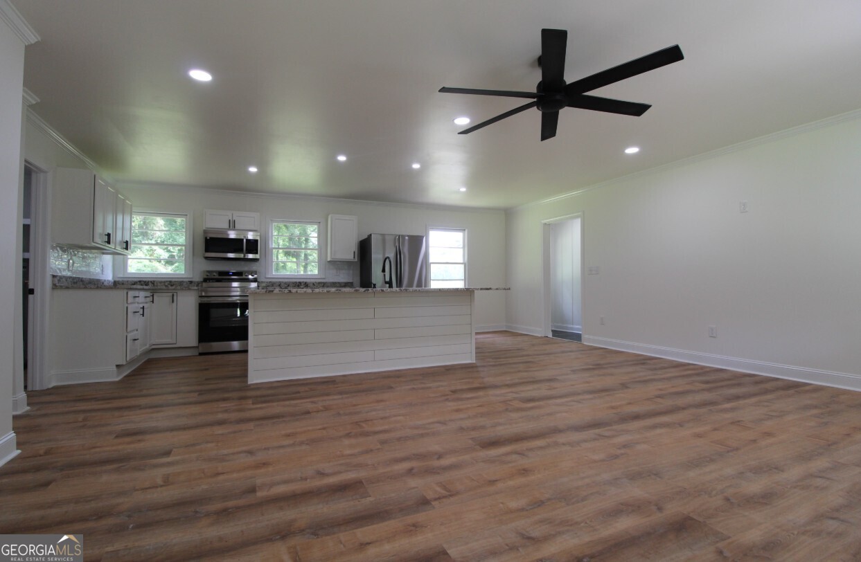 8142 Alabama Highway Rome, GA 30165 - Photo 2 of 10 an empty room with wooden floor a ceiling fan and kitchen view