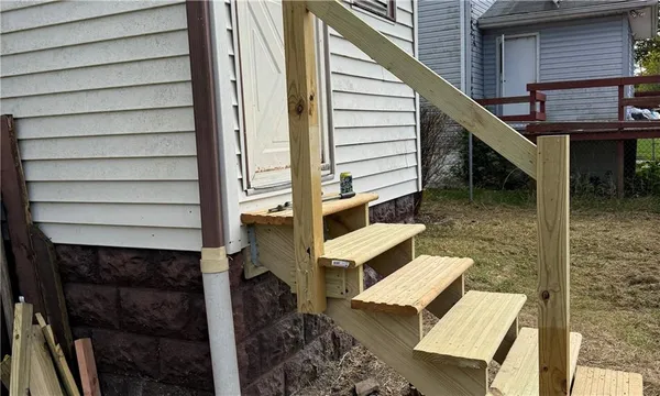 a view of house with wooden stairs and a large tree