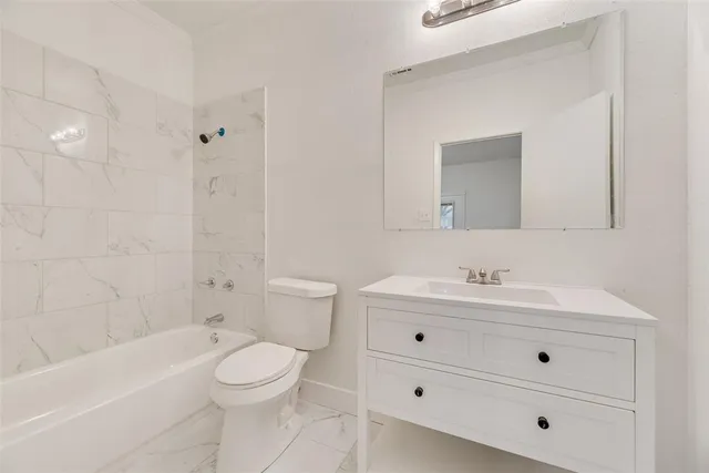 a bathroom with a toilet a sink a mirror a bathtub and vanity