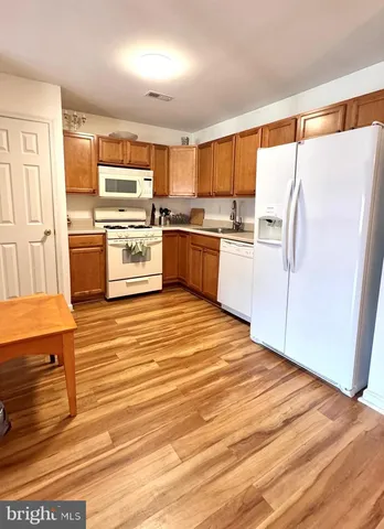 a kitchen with granite countertop a refrigerator cabinets and wooden floor