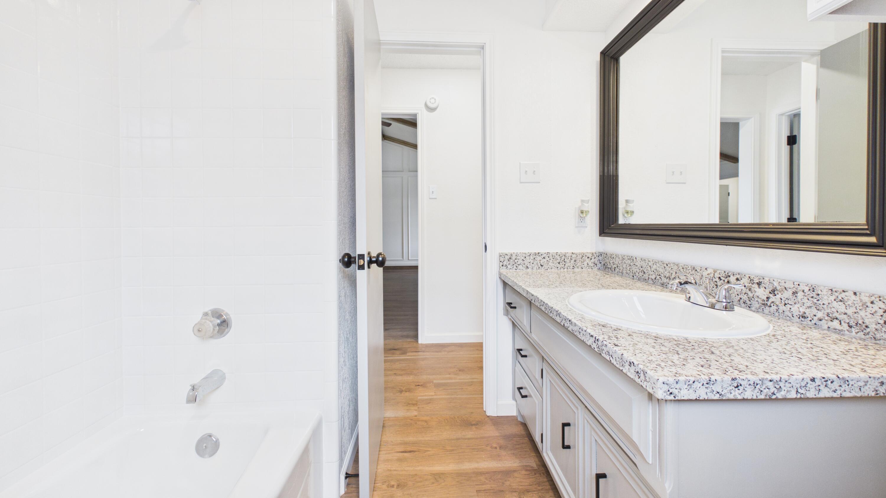 6902 Homestead Avenue Lubbock, TX 79424 - Photo 11 of 17 a bathroom with a granite countertop sink and a mirror