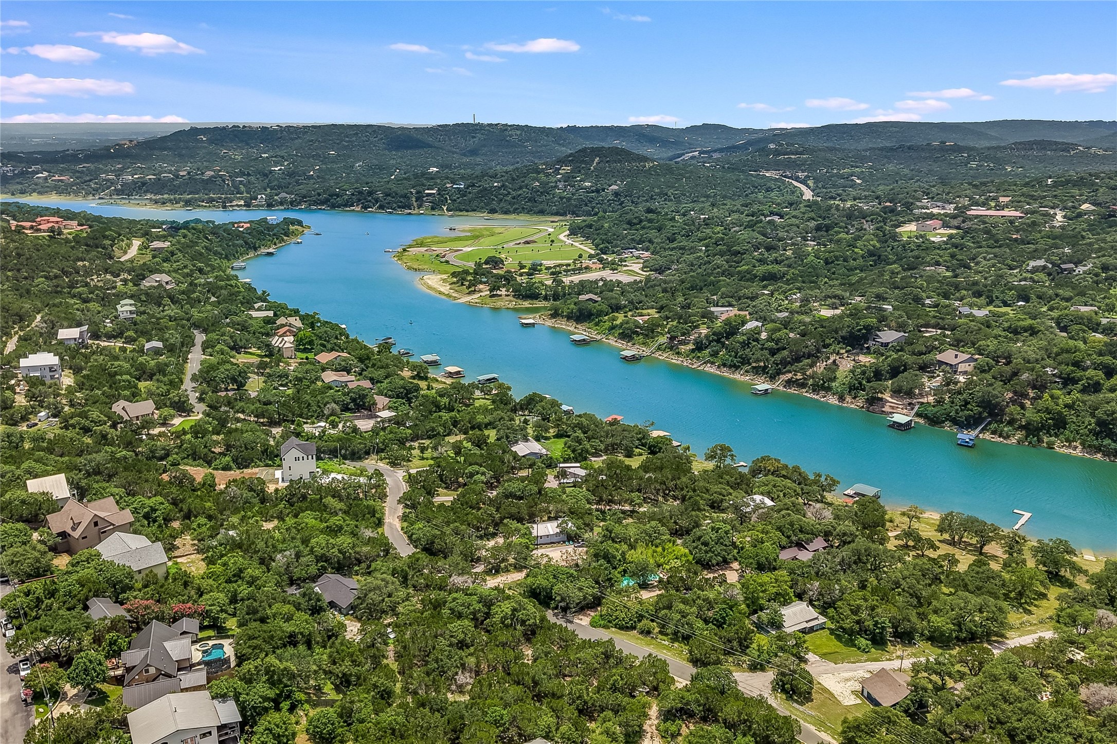 11104 Beach Road Leander, TX 78641 - Photo 5 of 15 A picturesque landscape showcases a tranquil lake winding through verdant hillsides dotted with homes.