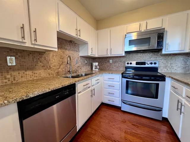 a kitchen with granite countertop white cabinets and appliances