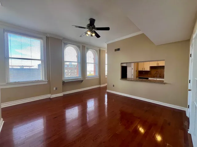 a view of an empty room with wooden floor and a window