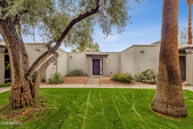 a front view of a house with a yard and potted plants
