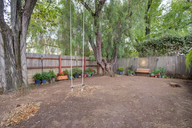 a view of a backyard with large tree and wooden fence