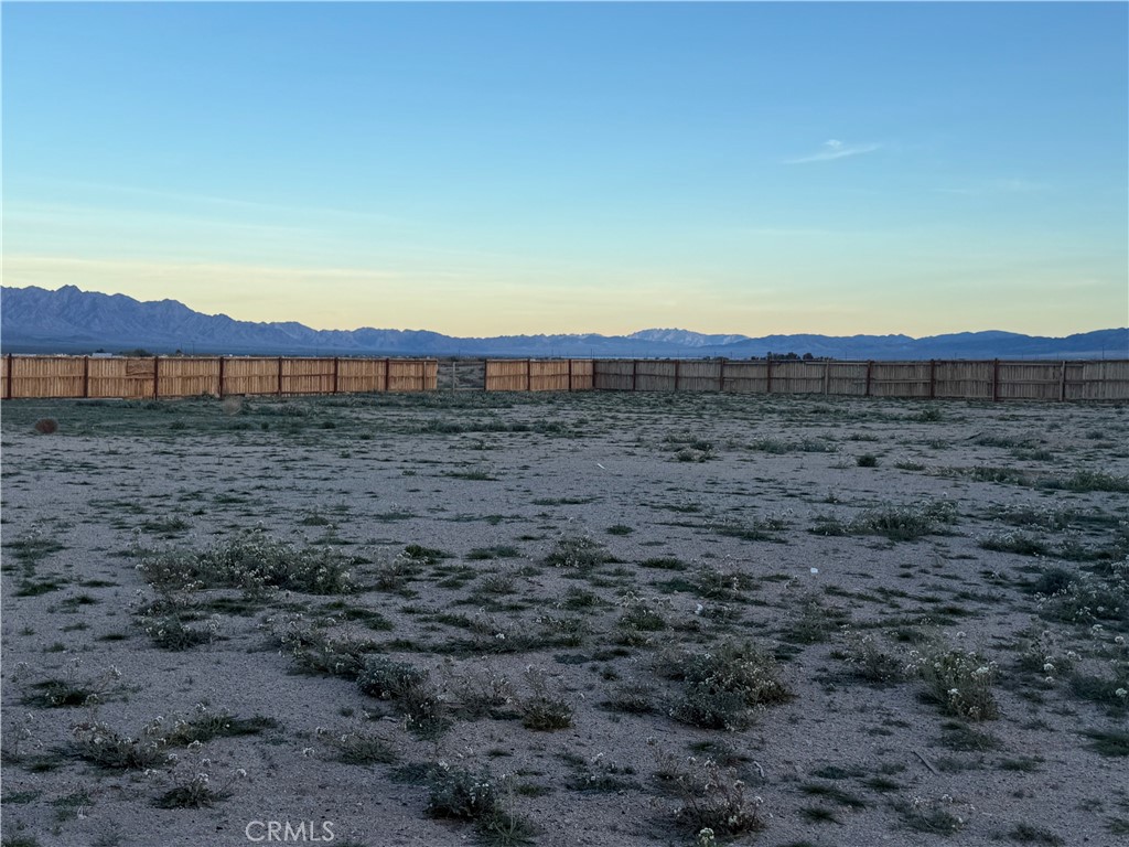 81818 Carey Road Twentynine Palms, CA 92277 - Photo 7 of 7 a view of a dry yard with wooden fence and mountain view