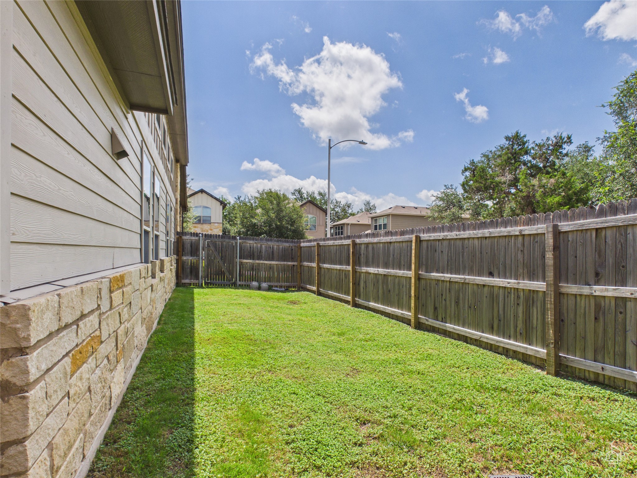 9310 Tanager Way Austin, TX 78748 - Photo 26 of 32 A well-maintained side yard with a sturdy privacy fence defines the outdoor space.