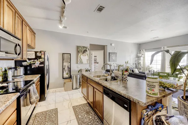 a kitchen with granite countertop kitchen island stainless steel appliances a sink counter space and a window