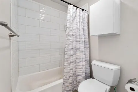 a white toilet sitting next to a bath tub