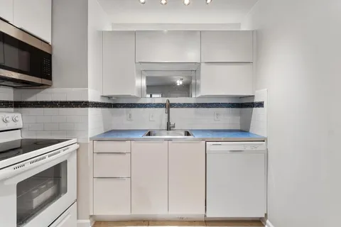 a kitchen with white cabinets stainless steel appliances and sink
