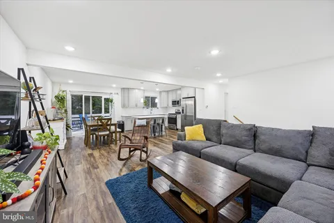 a living room with furniture kitchen view and a wooden floor
