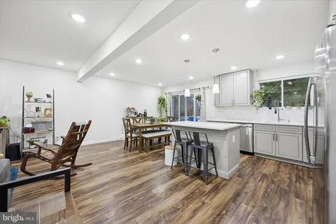 a kitchen with stainless steel appliances kitchen island granite countertop lots of white cabinets a dining table and chairs