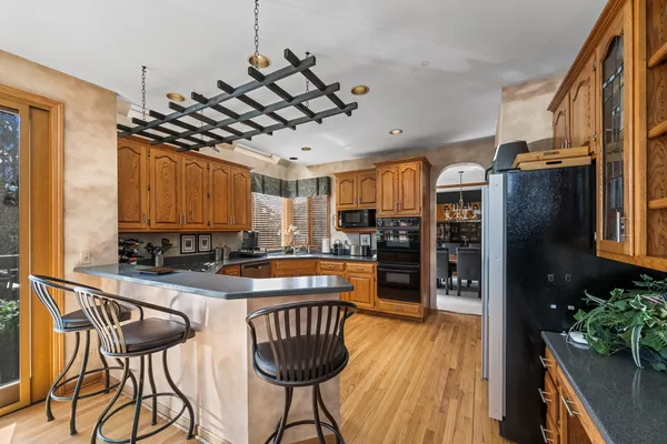 a kitchen with stainless steel appliances kitchen island granite countertop a table chairs and a refrigerator