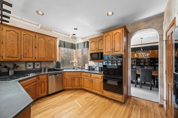 a kitchen with stainless steel appliances granite countertop a stove top oven a sink and dishwasher a refrigerator with wooden floor