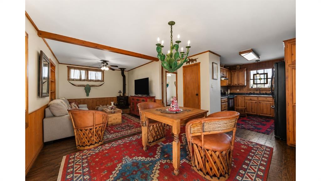 117 Reading Avenue North Center Point, TX 78010 - Photo 10 of 20 Open-concept living area featuring a decorative chandelier, wood-finish flooring, wood paneling, and exposed ceiling beams