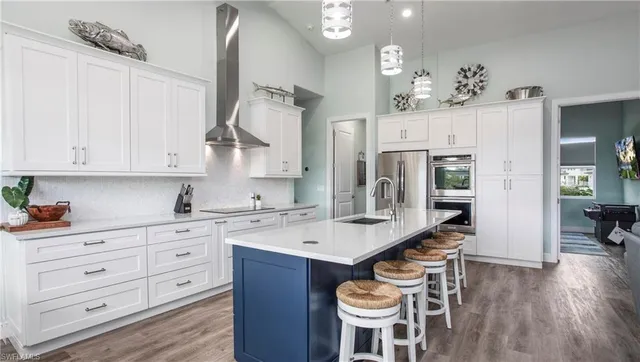 a open kitchen with a refrigerator a sink dishwasher and white cabinets with wooden floor