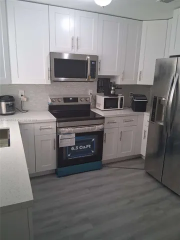 a kitchen with a stove a microwave a sink and a window