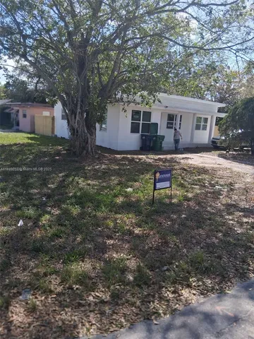 a backyard of a house with wooden fence and a tree