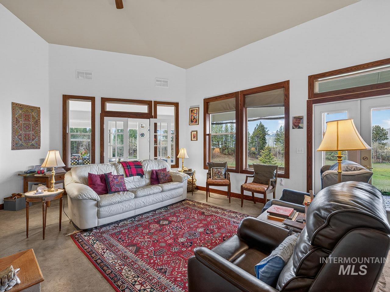 10885 Callender Road Cascade, ID 83611 - Photo 15 of 31 Spacious living area featuring a vaulted ceiling, wood-trimmed windows, and glass paneled double doors