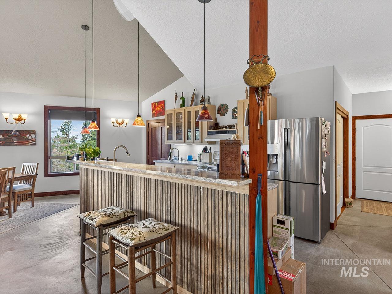 10885 Callender Road Cascade, ID 83611 - Photo 17 of 31 Kitchen area featuring a wood-panel accent island with a light-toned countertop, stainless steel refrigerator, and recessed cabinetry