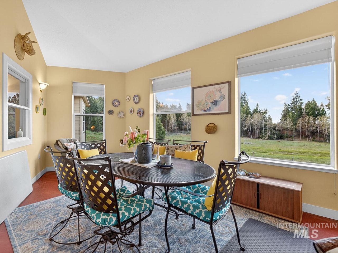 10885 Callender Road Cascade, ID 83611 - Photo 20 of 31 Dining area featuring multiple windows, a light yellow wall color, a textured area rug, and red-toned flooring