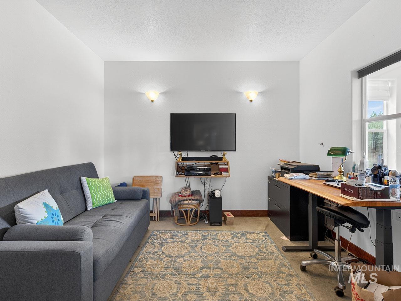10885 Callender Road Cascade, ID 83611 - Photo 22 of 31 Versatile room featuring light-toned walls, sconce lighting, and a window with a roller shade