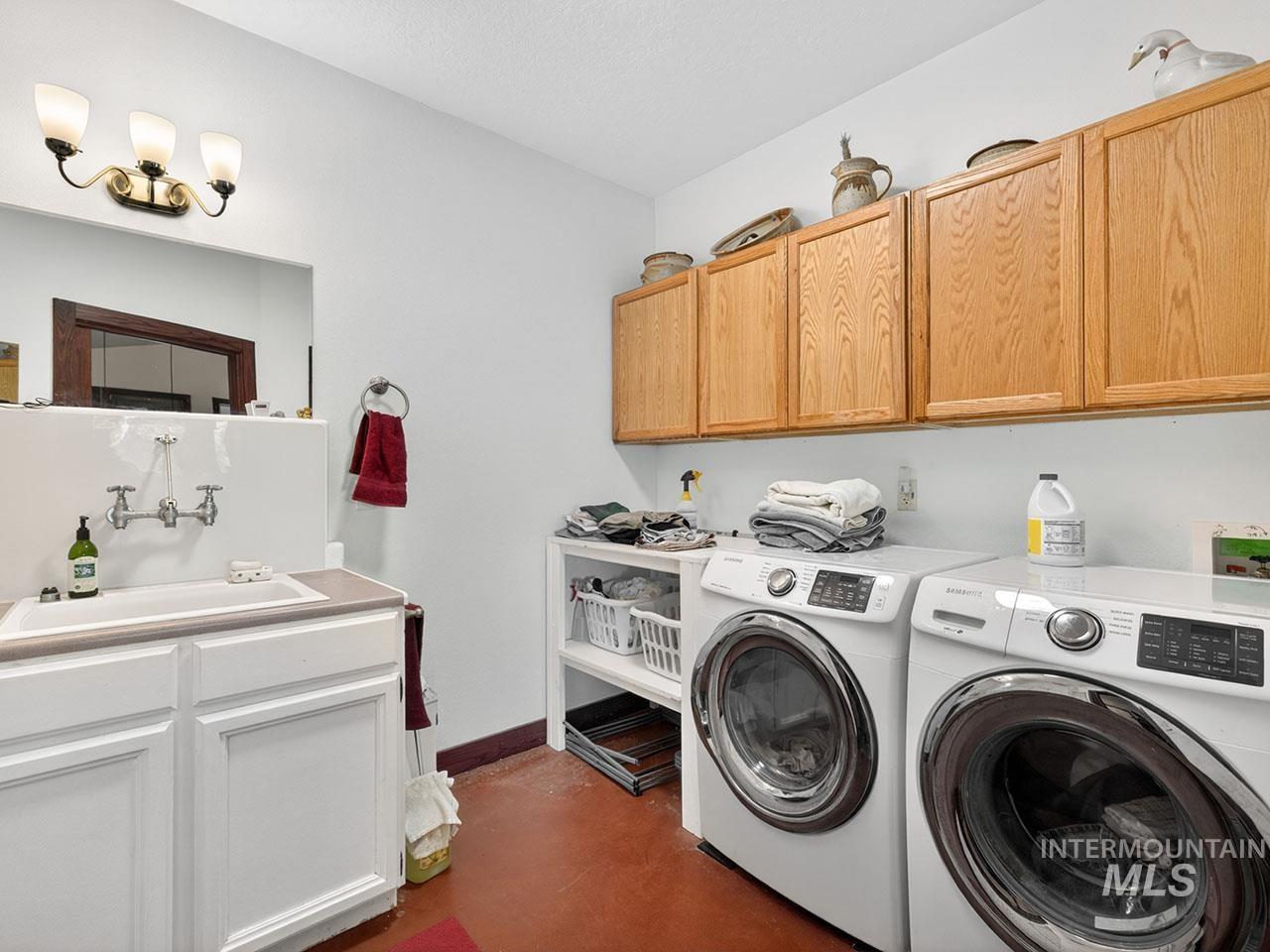 10885 Callender Road Cascade, ID 83611 - Photo 23 of 31 Dedicated laundry area featuring a utility sink, light wood cabinetry, and a dark tile floor