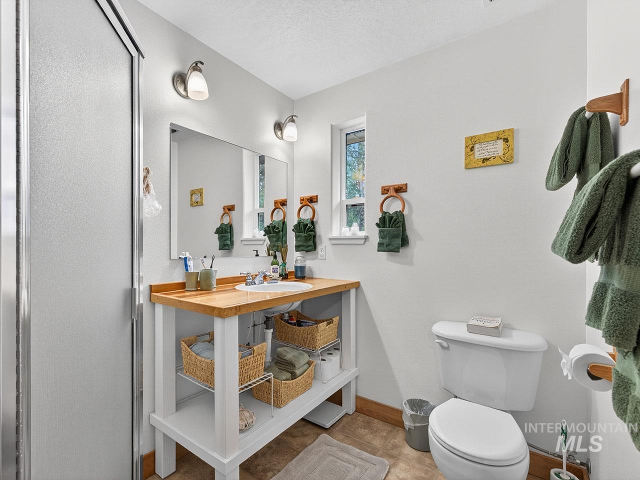 10885 Callender Road Cascade, ID 83611 - Photo 24 of 31 Bathroom featuring a frosted glass shower enclosure, a wood-finish vanity with an undermount sink, and a white toilet