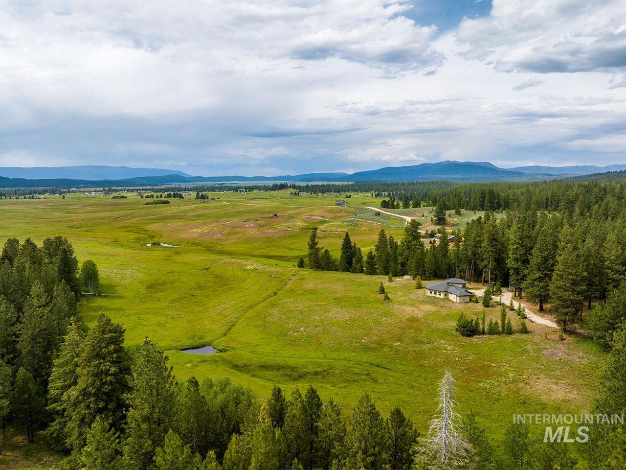 10885 Callender Road Cascade, ID 83611 - Photo 3 of 31 Expansive landscape featuring rolling green fields, abundant mature evergreen trees, distant mountains, and a secluded residence